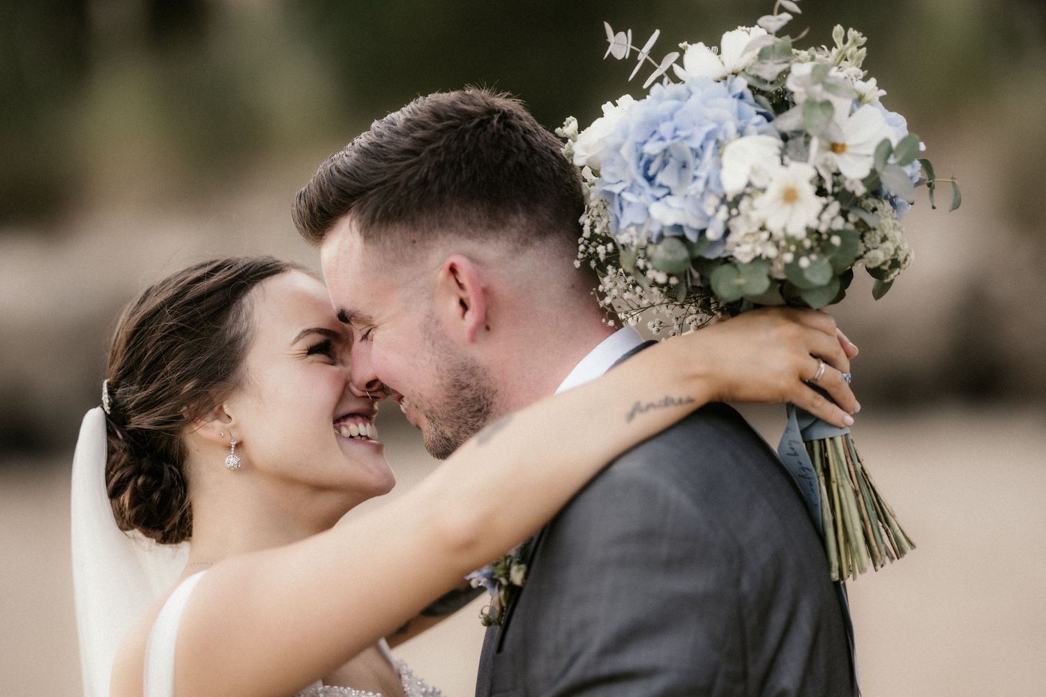 A couple shares a romantic moment during their wedding photoshoot with soft lighting and floral bouquet.