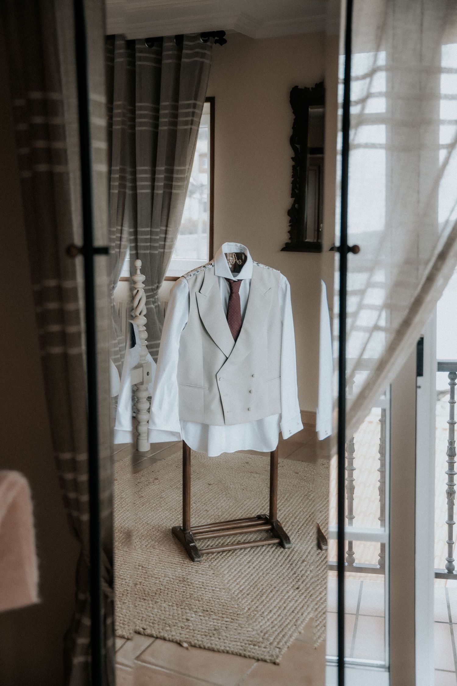 White formal blazer jacket hanging against a textured wall with soft natural lighting.