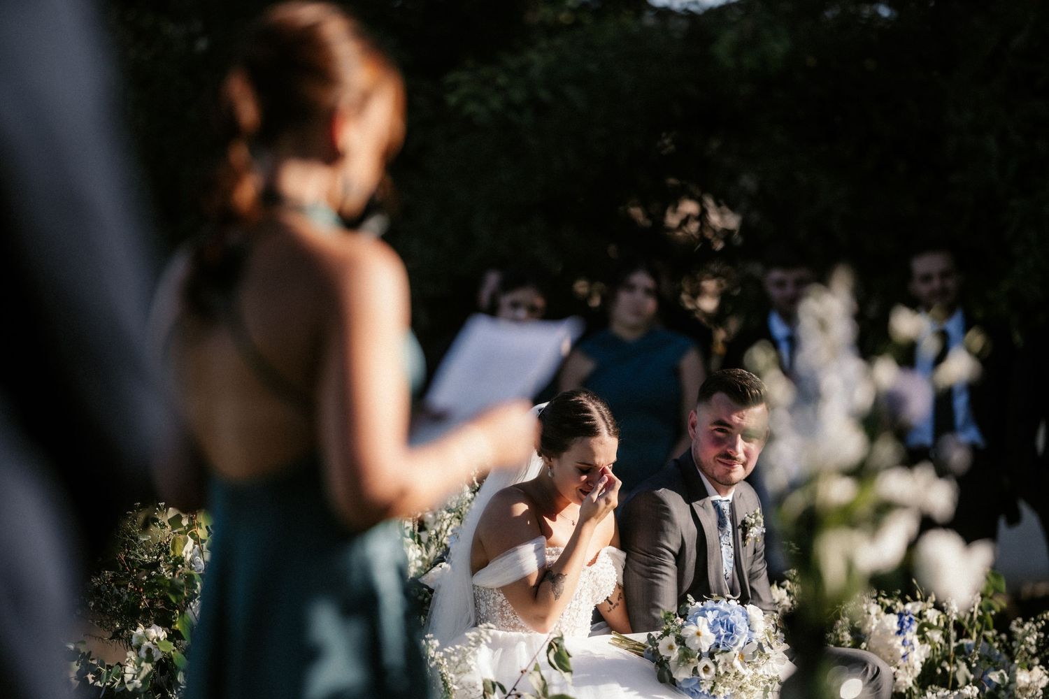 Emotional outdoor wedding ceremony with couple exchanging vows under natural lighting.
