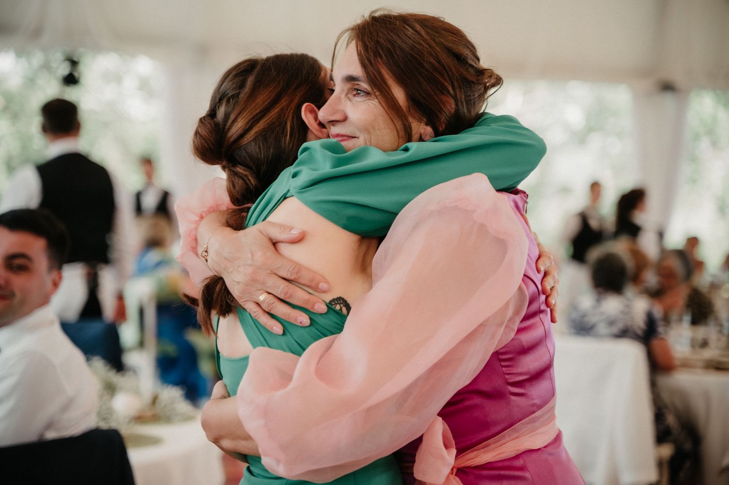 Wedding guests share heartfelt hugs during an emotional reception moment.