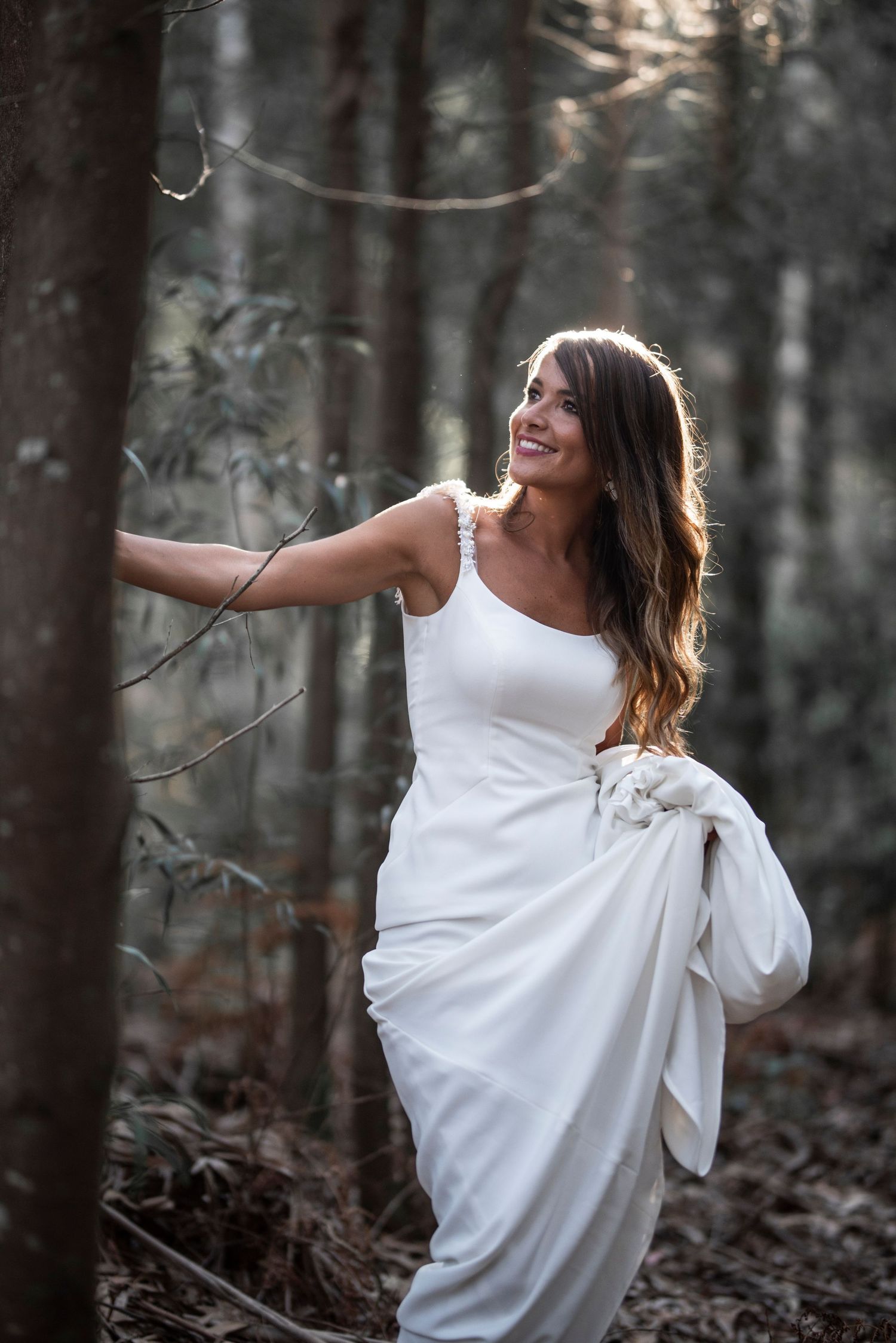 A figure in a flowing white dress dances gracefully through a misty forest setting.