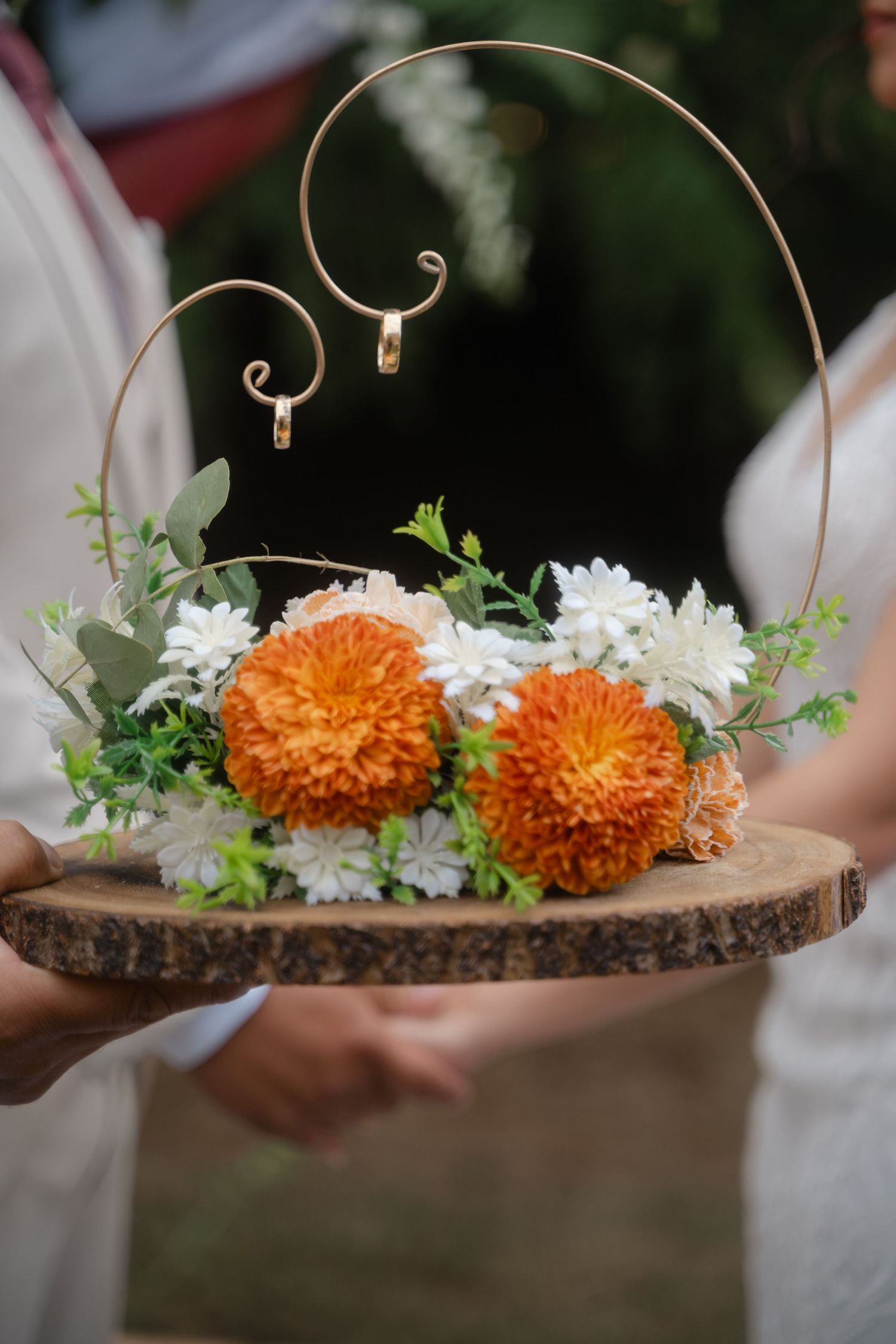 Rustic wood slice centerpiece decorated with orange marigolds, white flowers and gold wire accents.