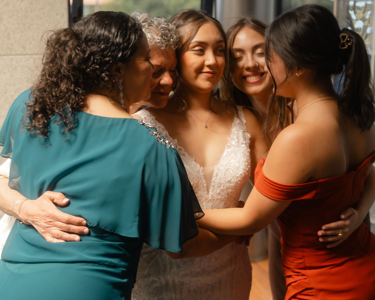 Group wearing formal attire in teal and rust colors sharing embraces.