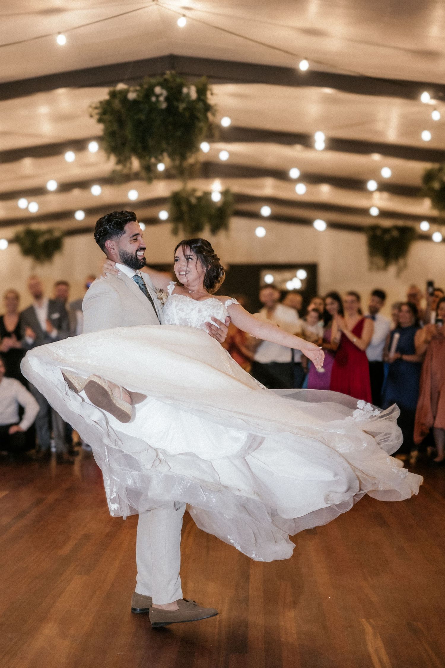 A couple performs an elegant dance move at a wedding reception with the bride's dress flowing dramatically.