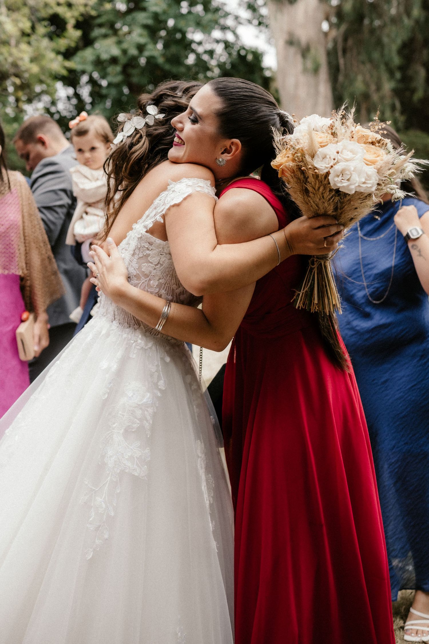 Wedding party in white dresses and red bridesmaid gowns gather outdoors for group photos.
