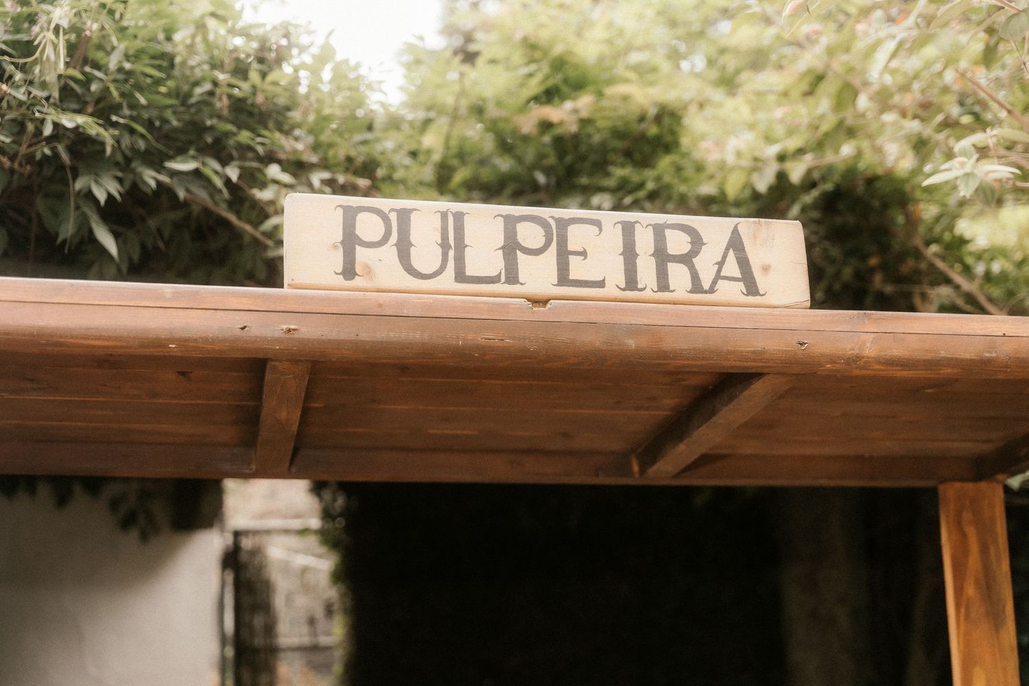 Wooden sign reading 'Pulpeira' mounted on rustic beam structure in natural outdoor setting.