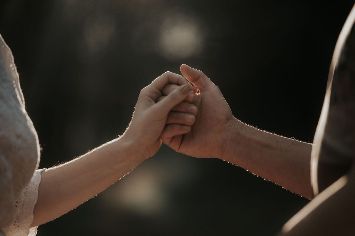 Three hands come together for a celebratory high-five gesture against a dark background.