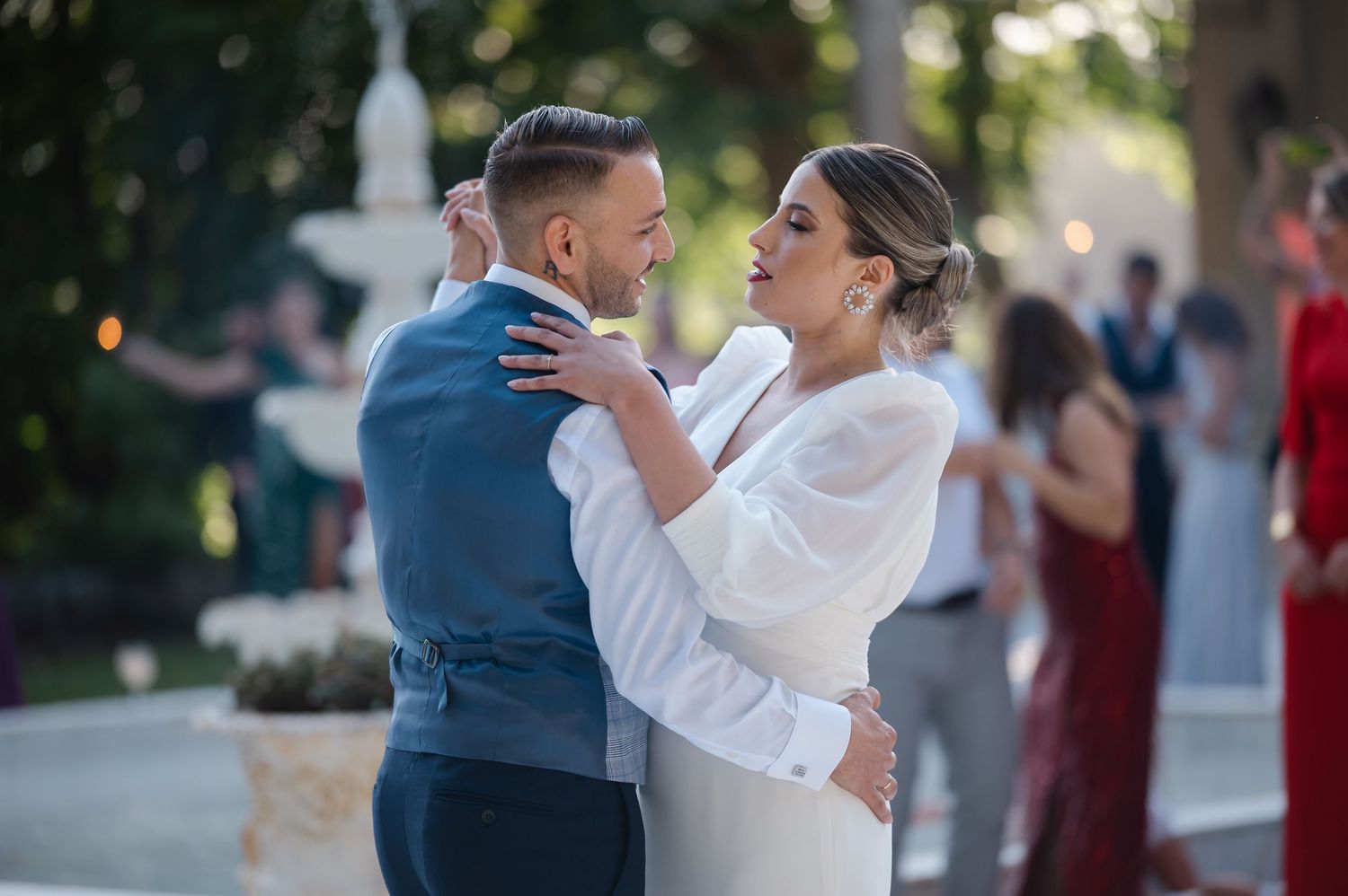 A couple shares a romantic dance moment outdoors at their wedding celebration.