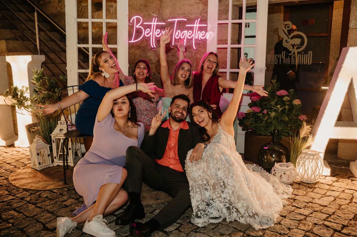 Wedding party dancing and celebrating on a stone patio at night with decorative lighting.
