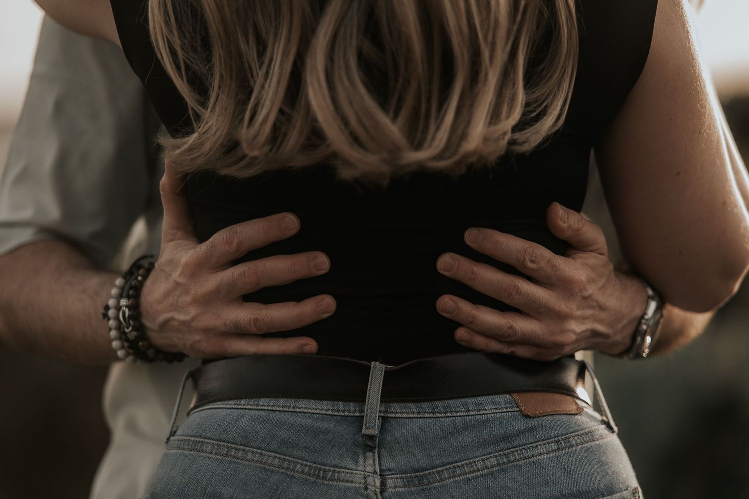 Close up shot of hands on waist wearing jeans, showing intimate body language in an artistic style.