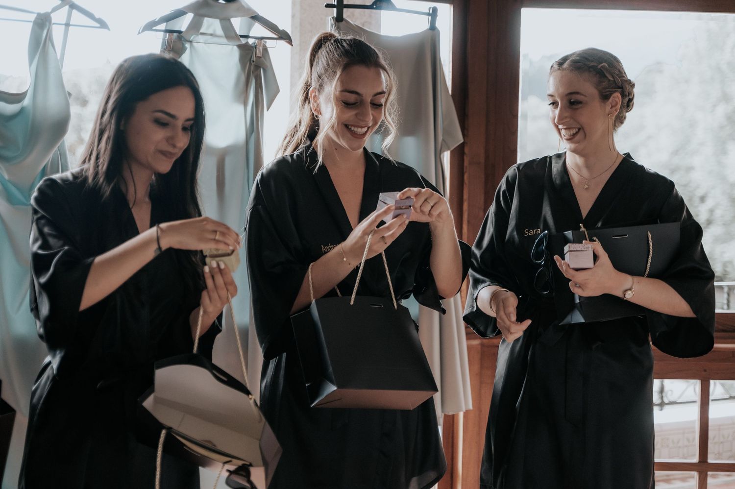 A group wearing black outfits sits together looking at something during a pre-wedding gathering.