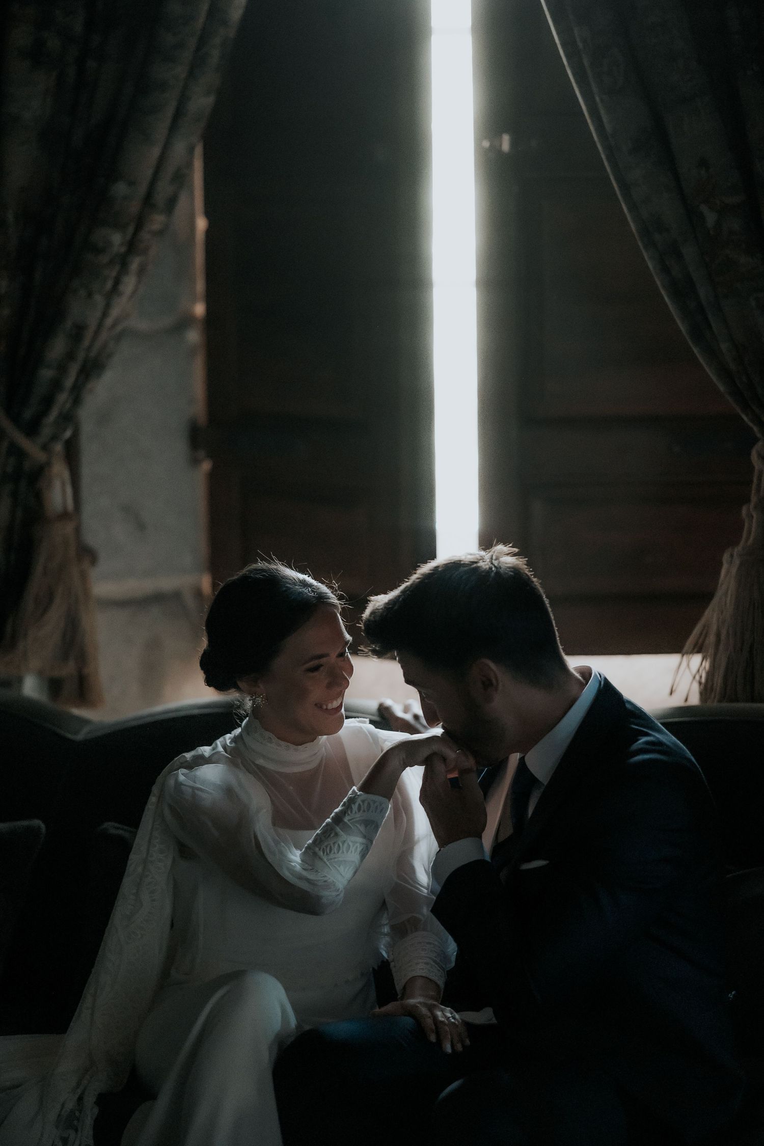 Intimate wedding couple moment captured in moody indoor lighting with dramatic shadows.