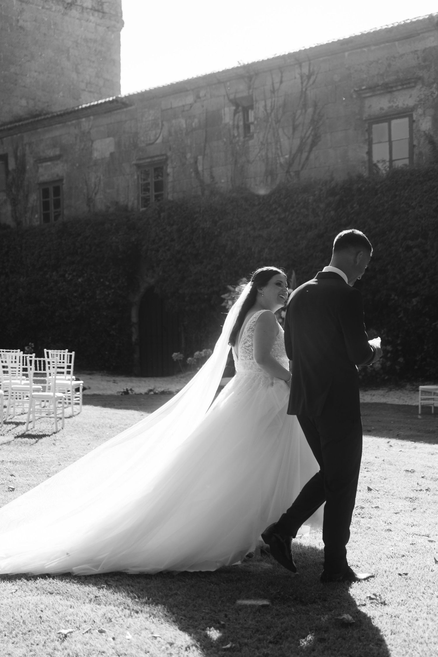 A series of black and white wedding photos showing the bride's flowing dress against a stone building backdrop.