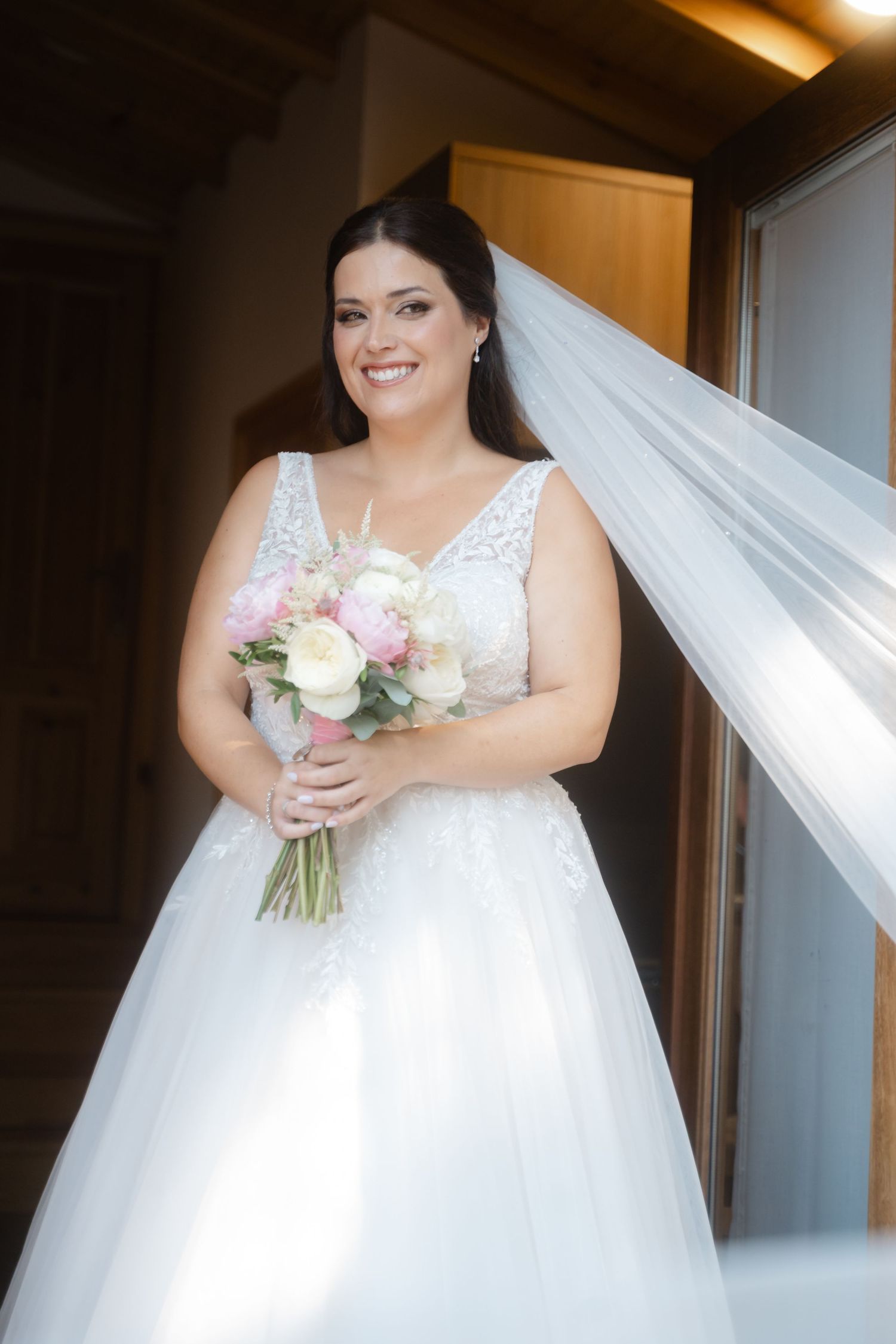 Multiple angles of someone wearing a lace-detailed wedding dress holding a delicate bouquet of pink and white flowers.
