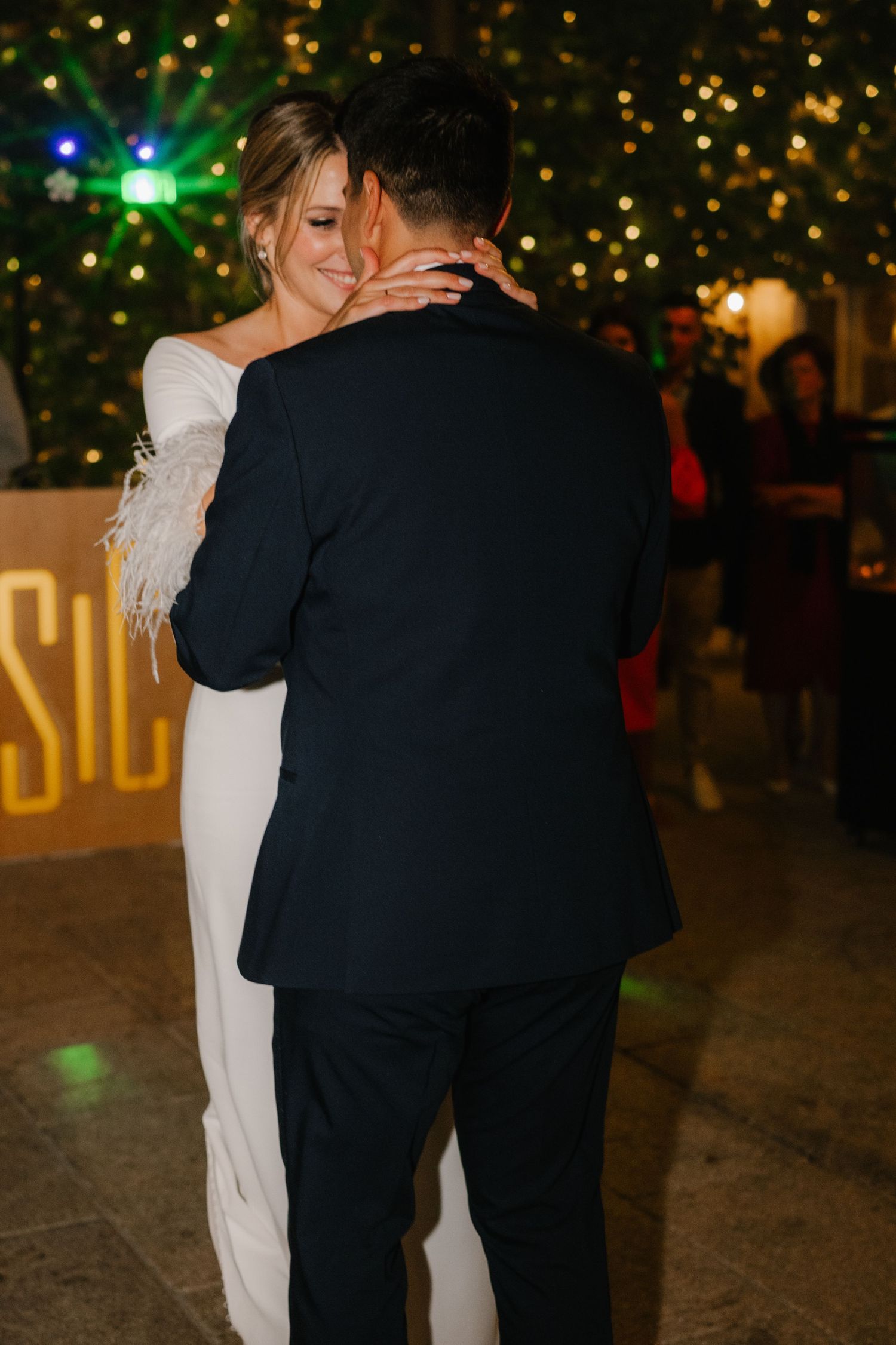 Newlyweds dance intimately surrounded by warm twinkle lights at their wedding reception.