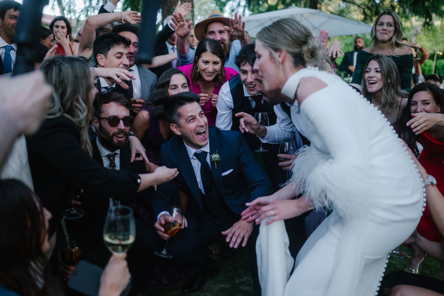 Joyful celebration at an outdoor wedding reception with guests dancing and mingling in formal attire.