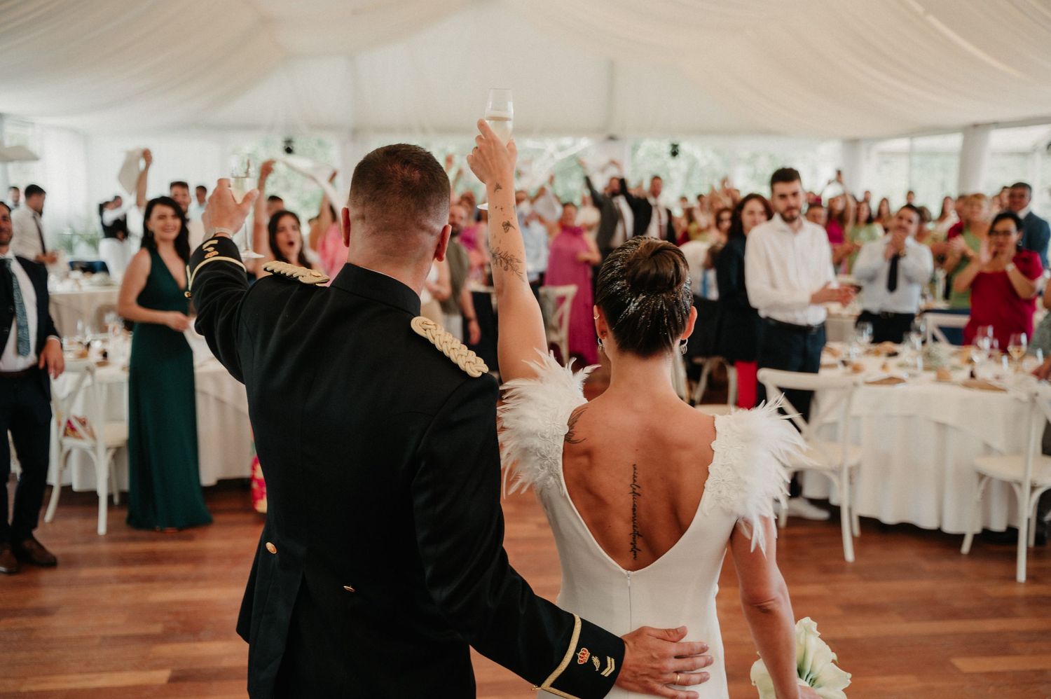 Wedding reception guests dance and celebrate together in an elegant white-draped venue.