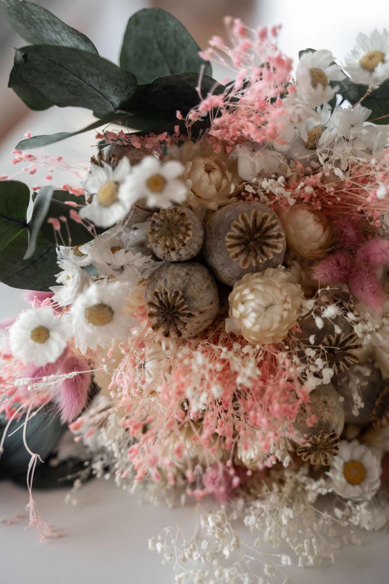 A delicate dried flower arrangement featuring pink and white blooms with preserved foliage in a romantic vintage style.