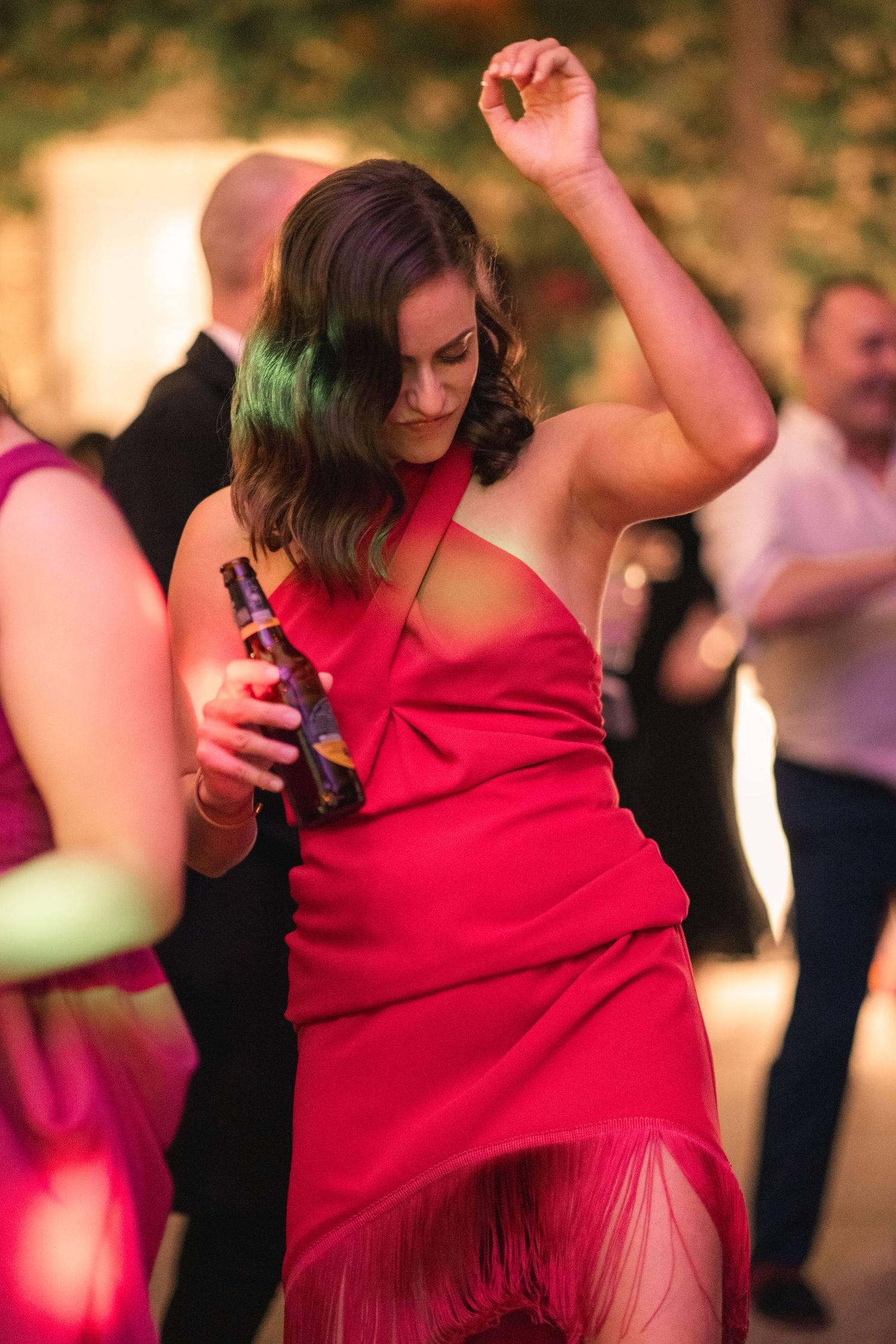 A person in a vibrant red dress dances energetically at an evening party or celebration.