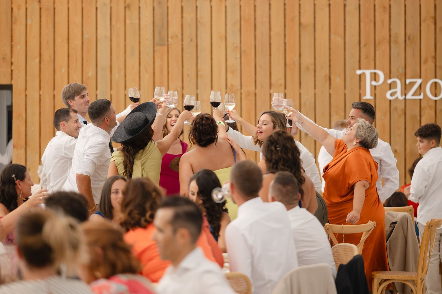 Large group of people in orange and white clothing standing in a wooden gymnasium during an event.