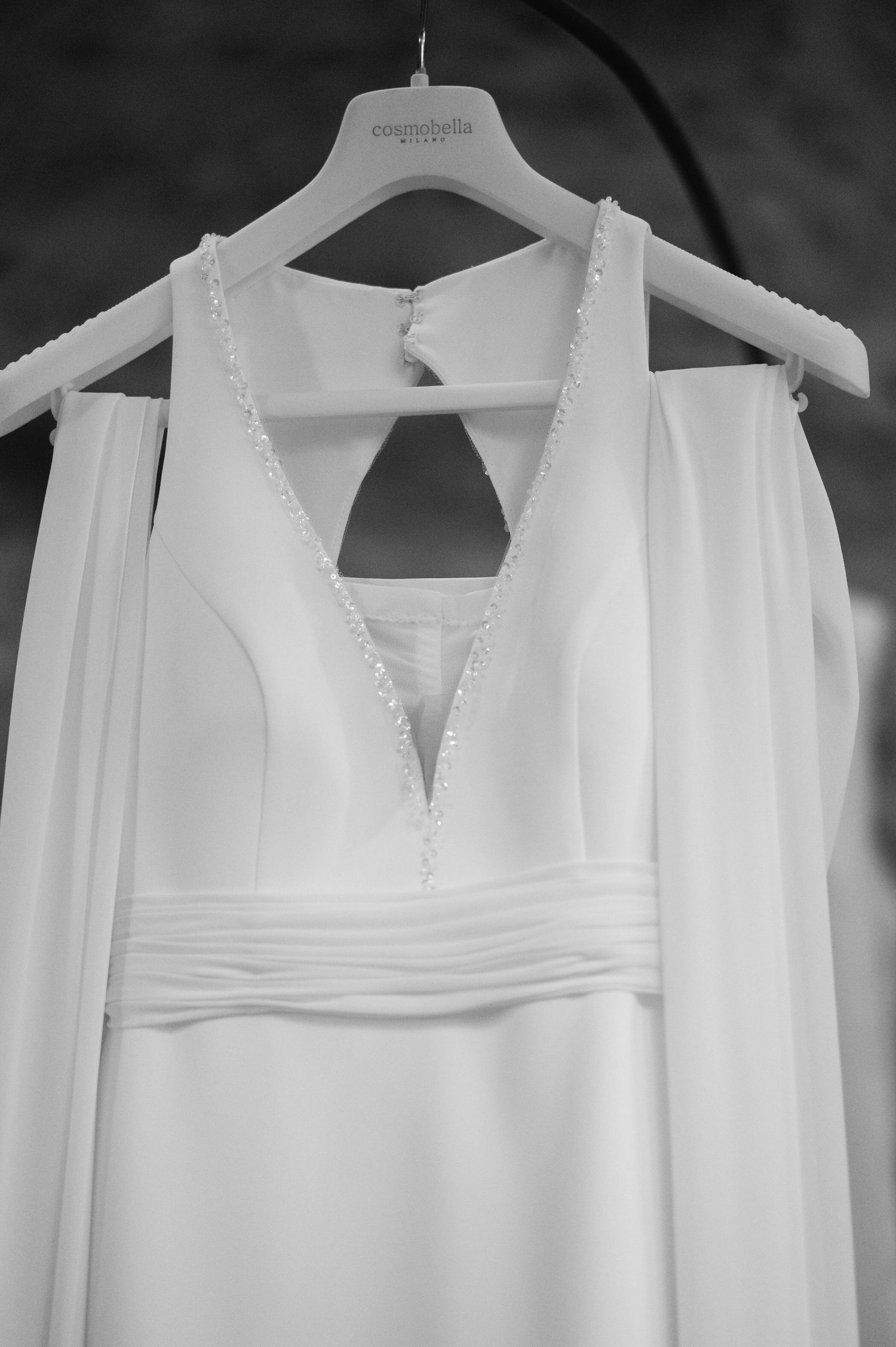 Multiple white wedding dresses hanging on display showcasing different neckline styles and details.