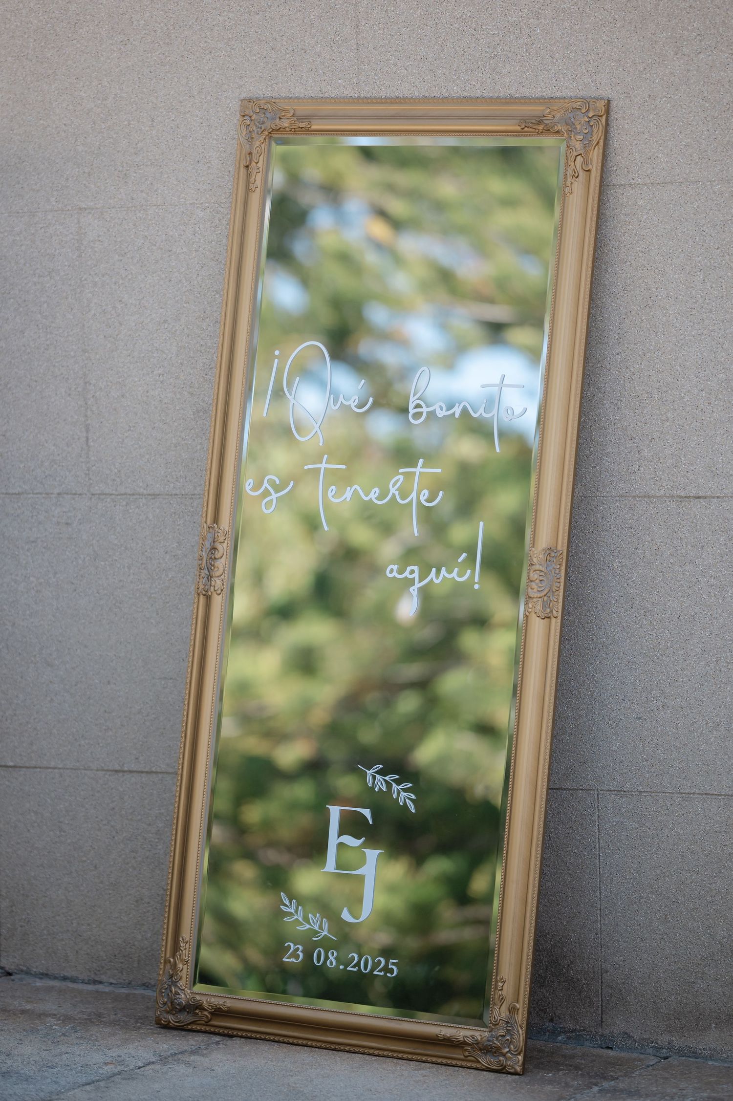 A series of ornate gold-framed mirrors with handwritten white text displayed against a gray concrete wall.