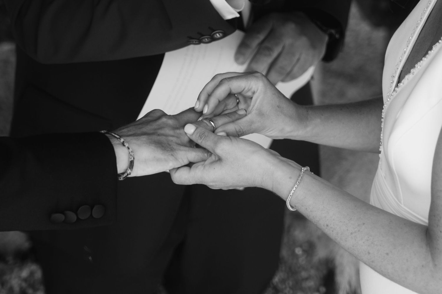 Close-up of hands working with a black and white document or paper on a table.