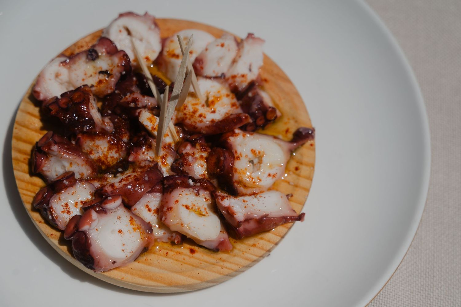Grilled octopus tentacles served on wooden boards and white plates with charred edges and seasonings.