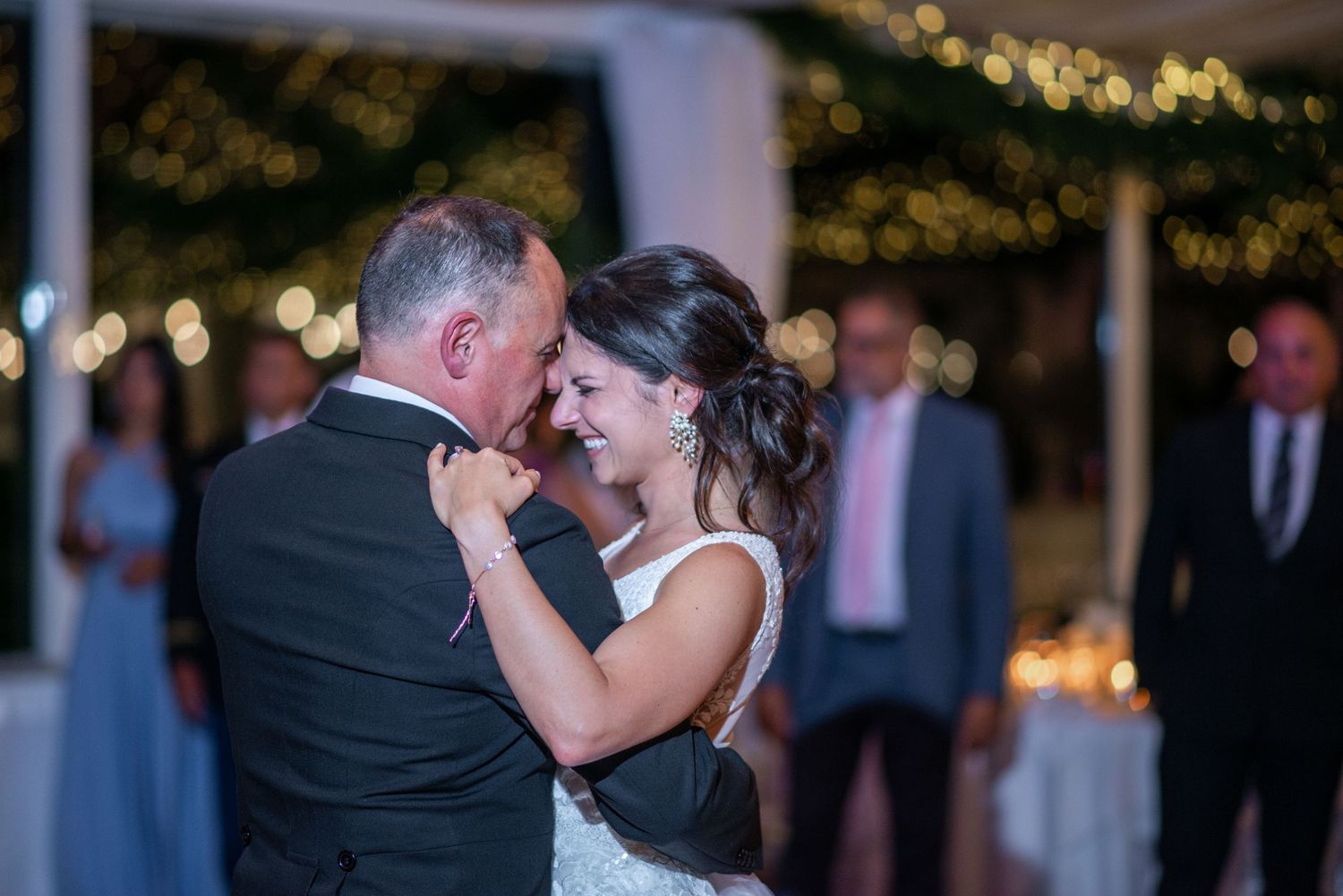 Wedding couple shares romantic dance moments under twinkling lights at evening reception.