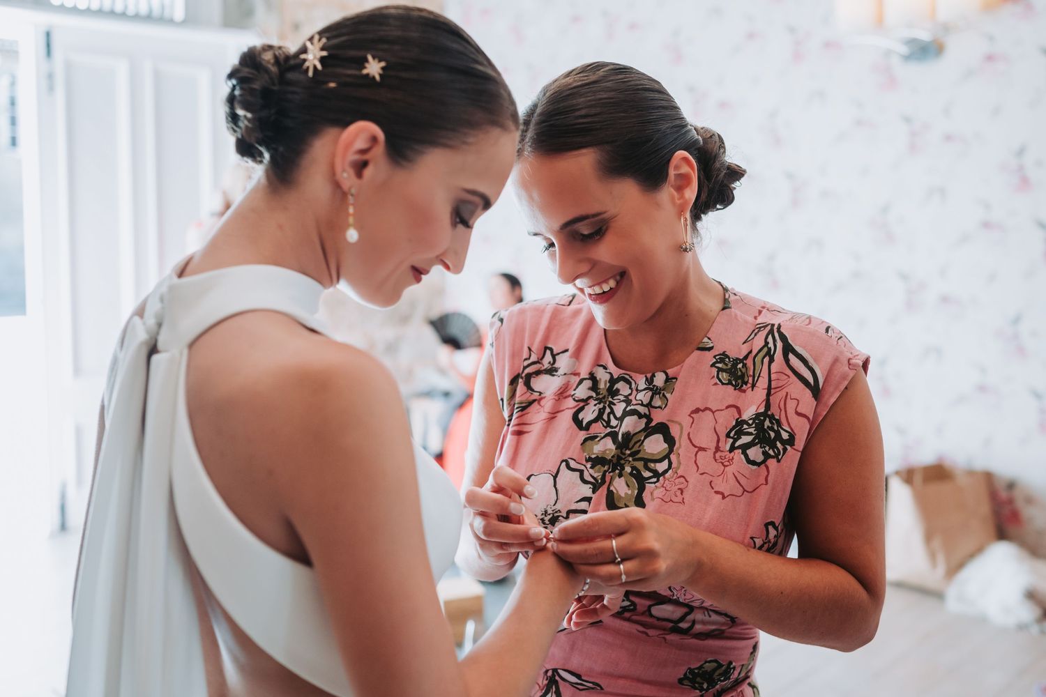 Group of bridesmaids in pink dresses looking at a phone together.