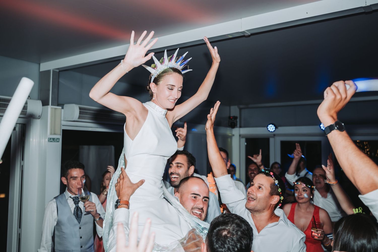 Joyful celebration on a dance floor with people raising their hands and dancing at an indoor event.