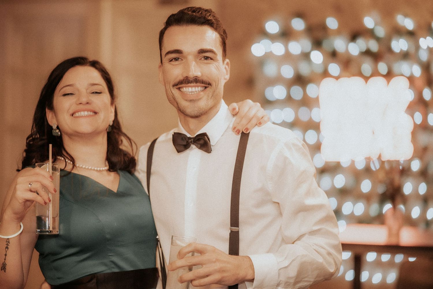 Guests celebrate at an elegant wedding reception with sparkling lights in the background.