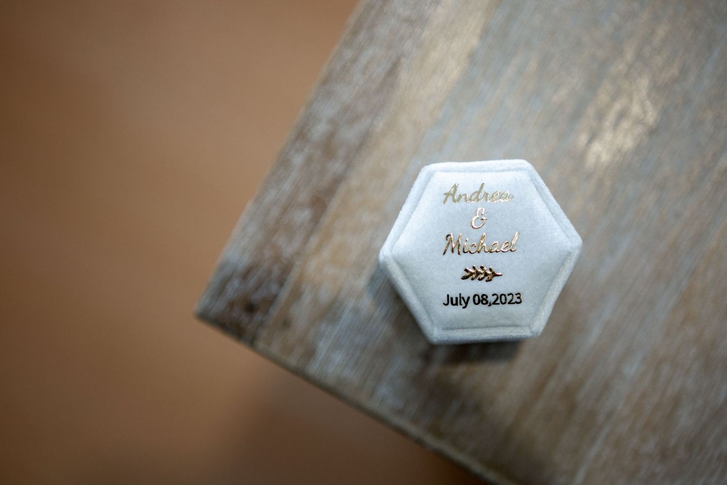 Close-up of a hexagonal wedding detail card on rustic wooden surface.