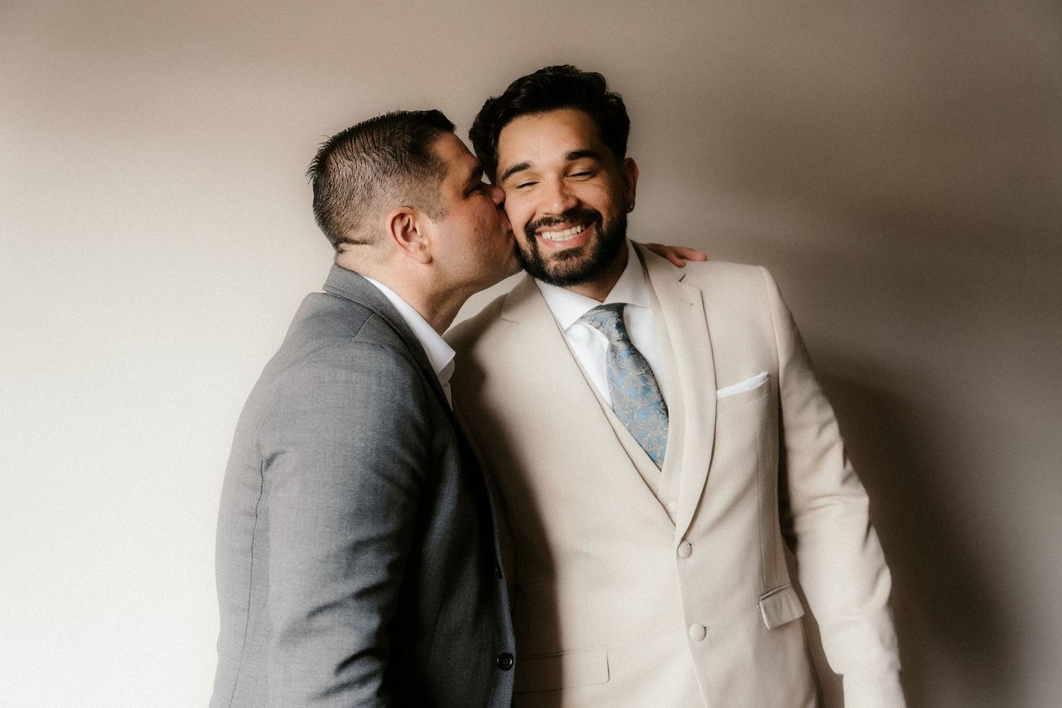 Two people in formal attire share an emotional embrace during what appears to be a wedding ceremony.