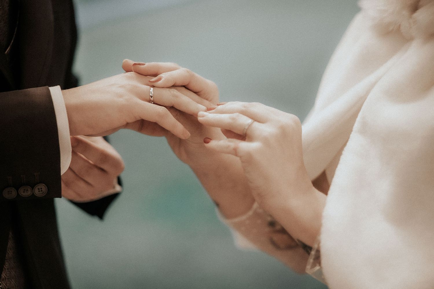 Close-up shot of hands exchanging wedding rings during an intimate ceremony.