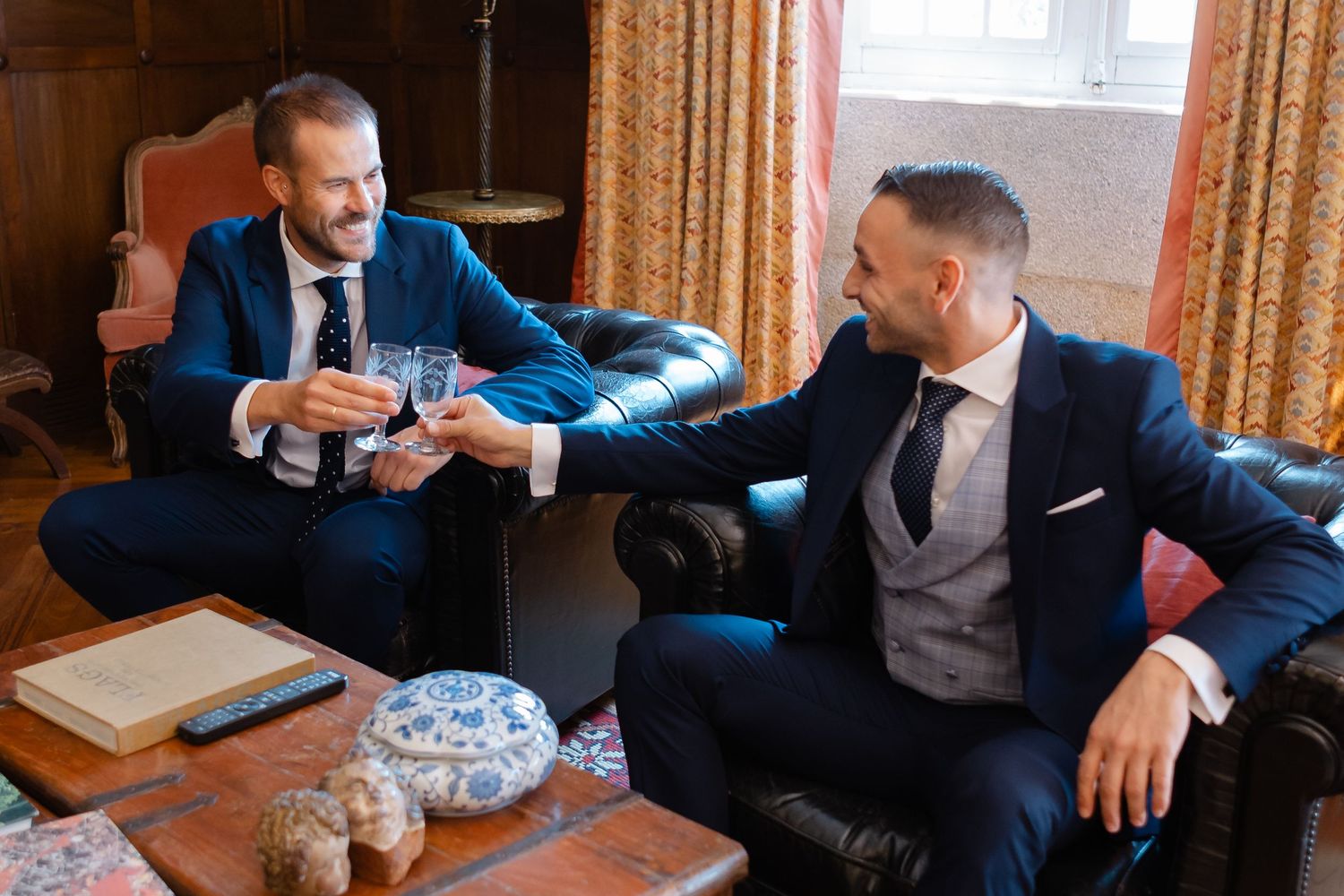 Business professionals in blue suits sit on couches during a casual meeting in a hotel lounge area.