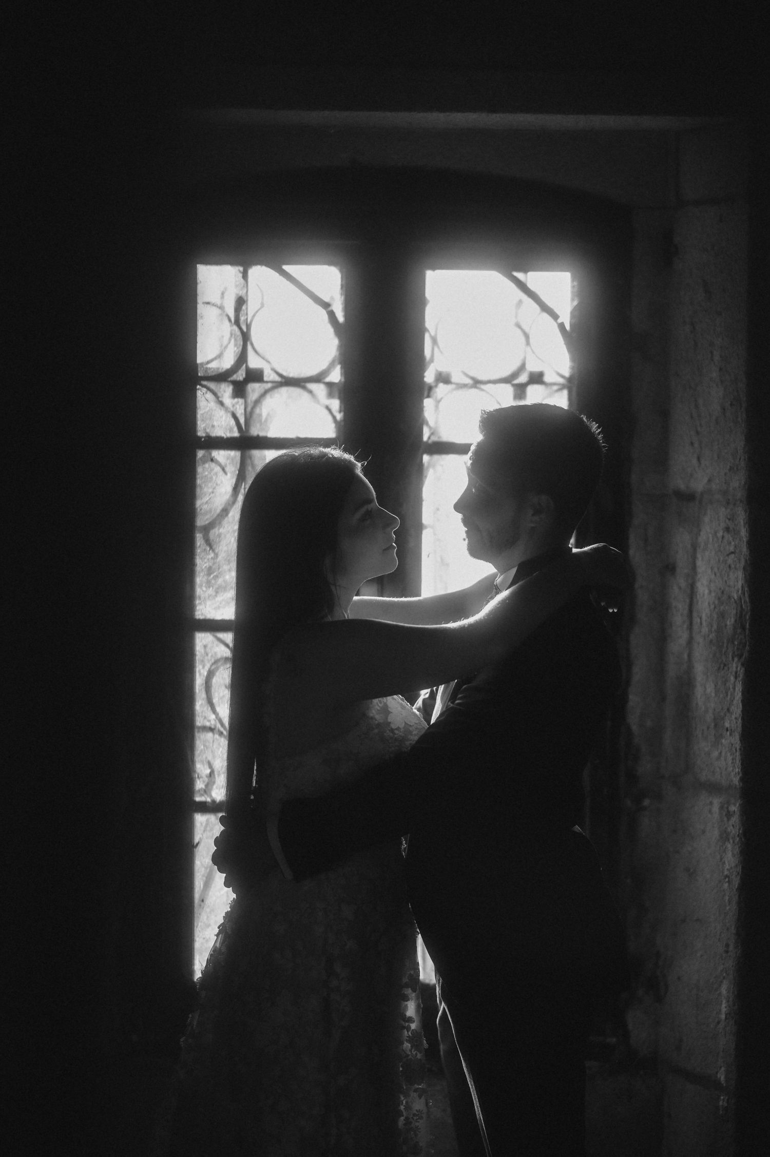 A silhouetted couple embraces near a window in a series of black and white photographs.