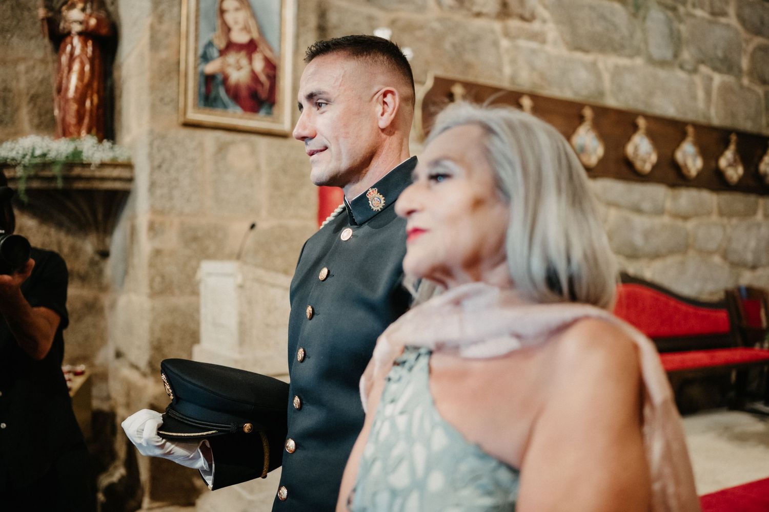 A couple shares a joyful moment during their wedding ceremony against a stone wall backdrop.