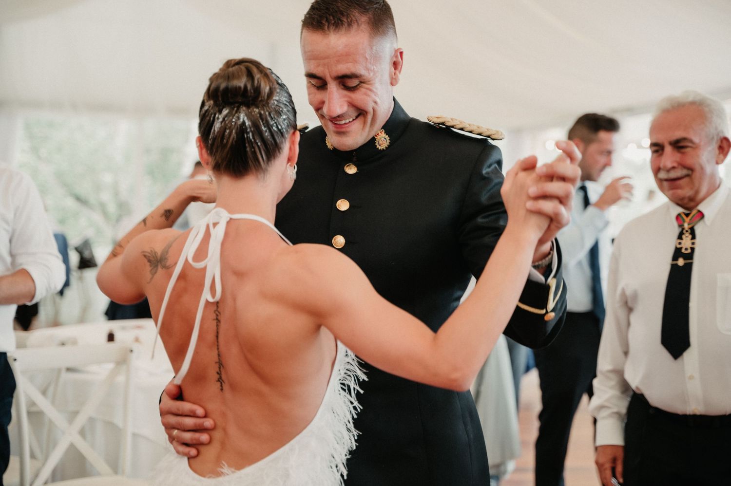 Wedding guests dance and celebrate together during a joyful reception under a white tent.
