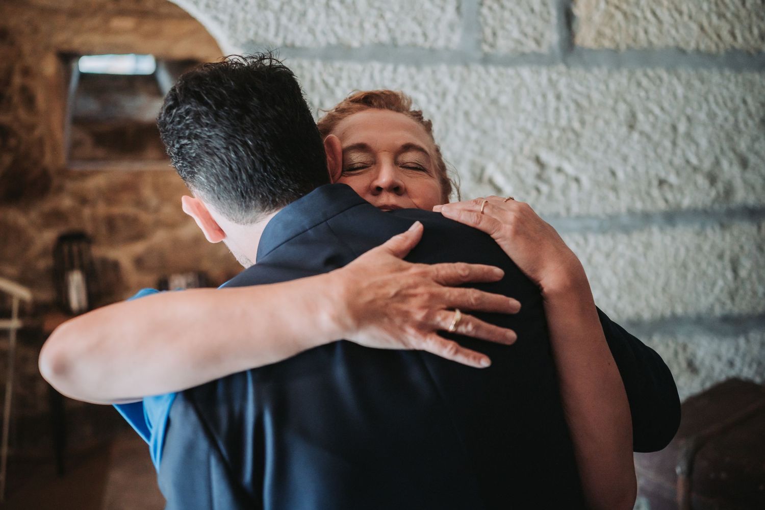 People sharing emotional embraces and hugs in a dimly lit indoor setting.