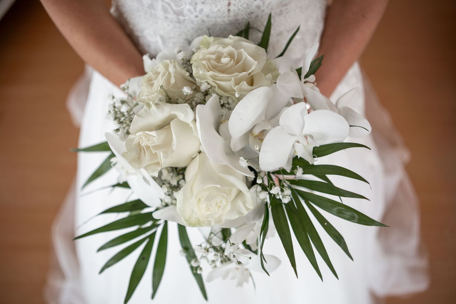 White bridal bouquet with roses, lilies and tropical palm leaves.