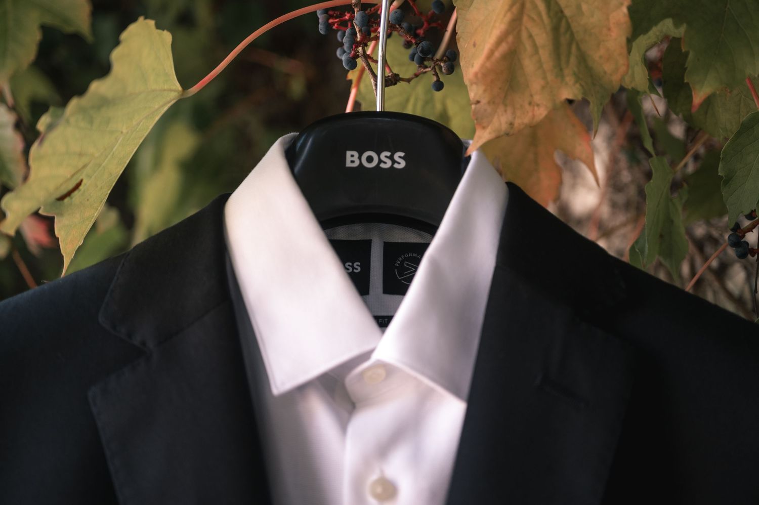 A close-up view of a black suit jacket with white dress shirt collar visible against a dark background.