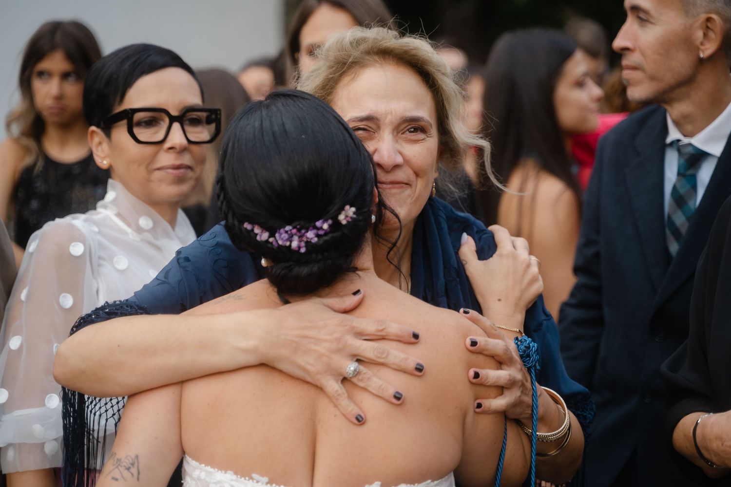 Wedding guests gather outdoors for a celebration with joyful expressions and formal attire.