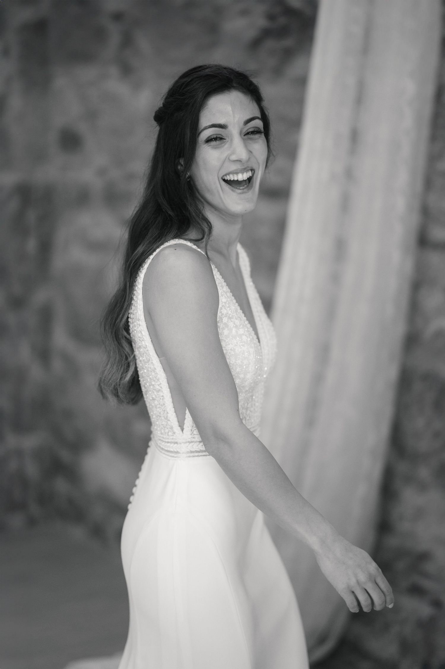 A candid black and white portrait capturing pure joy and laughter in a wedding dress.