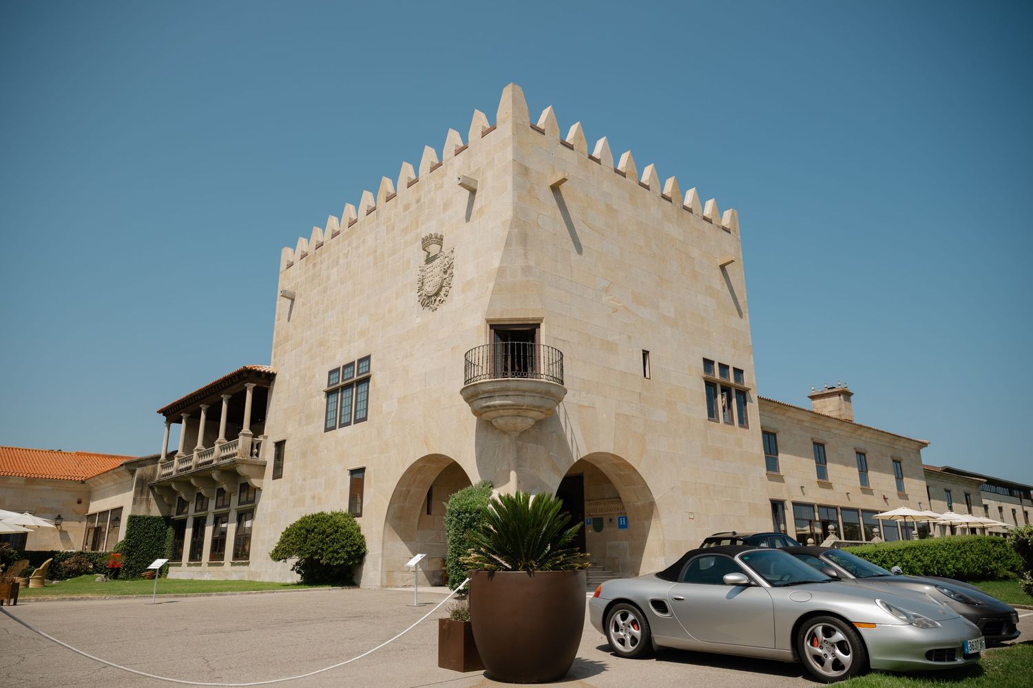 Exterior views of a modern white stucco building with architectural details and a parked sports car.