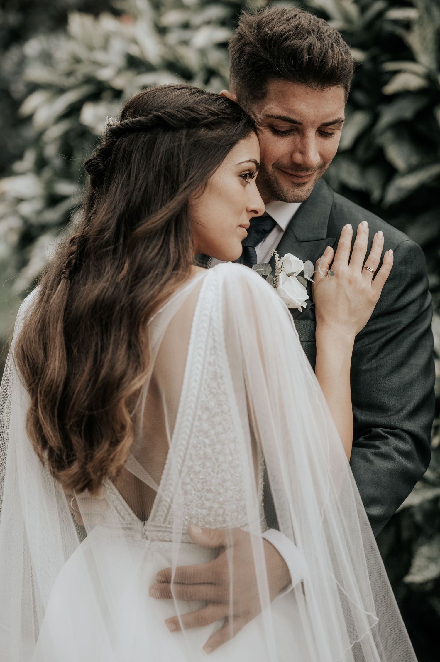 Intimate wedding portrait showing tender embrace against lush garden backdrop.