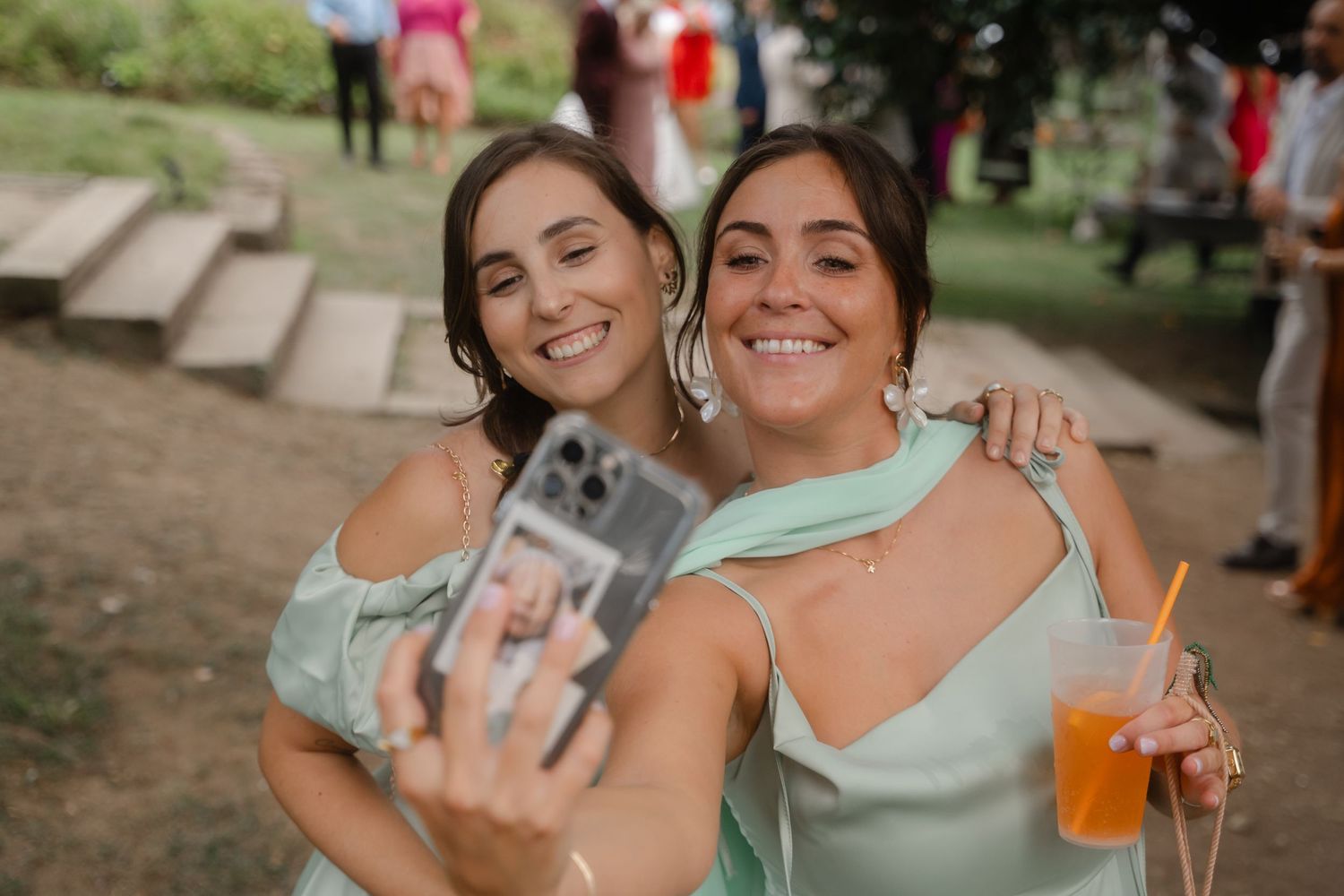 People celebrating outdoors with drinks and laughter at a casual social gathering in a park setting.