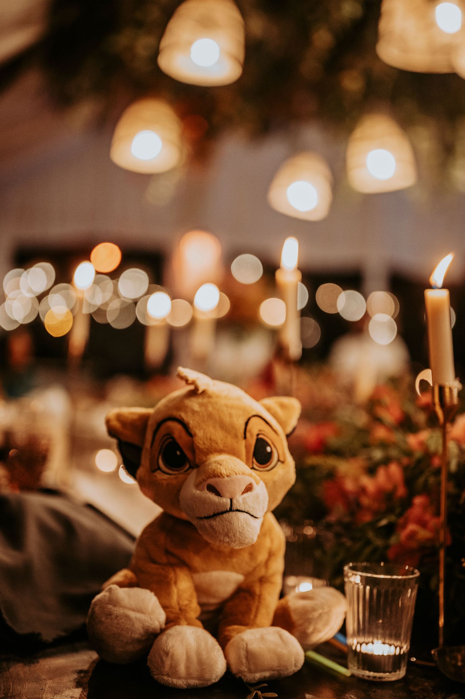 Cute plush lion toys arranged as table decorations with candlelight and bokeh lighting.