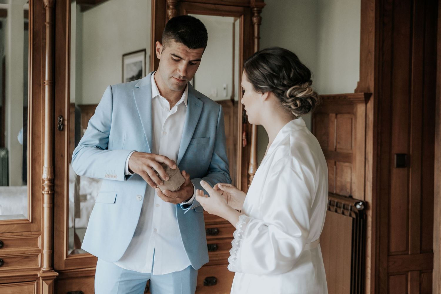 A couple in wedding attire shares an intimate moment in an elegant wood-paneled hallway.