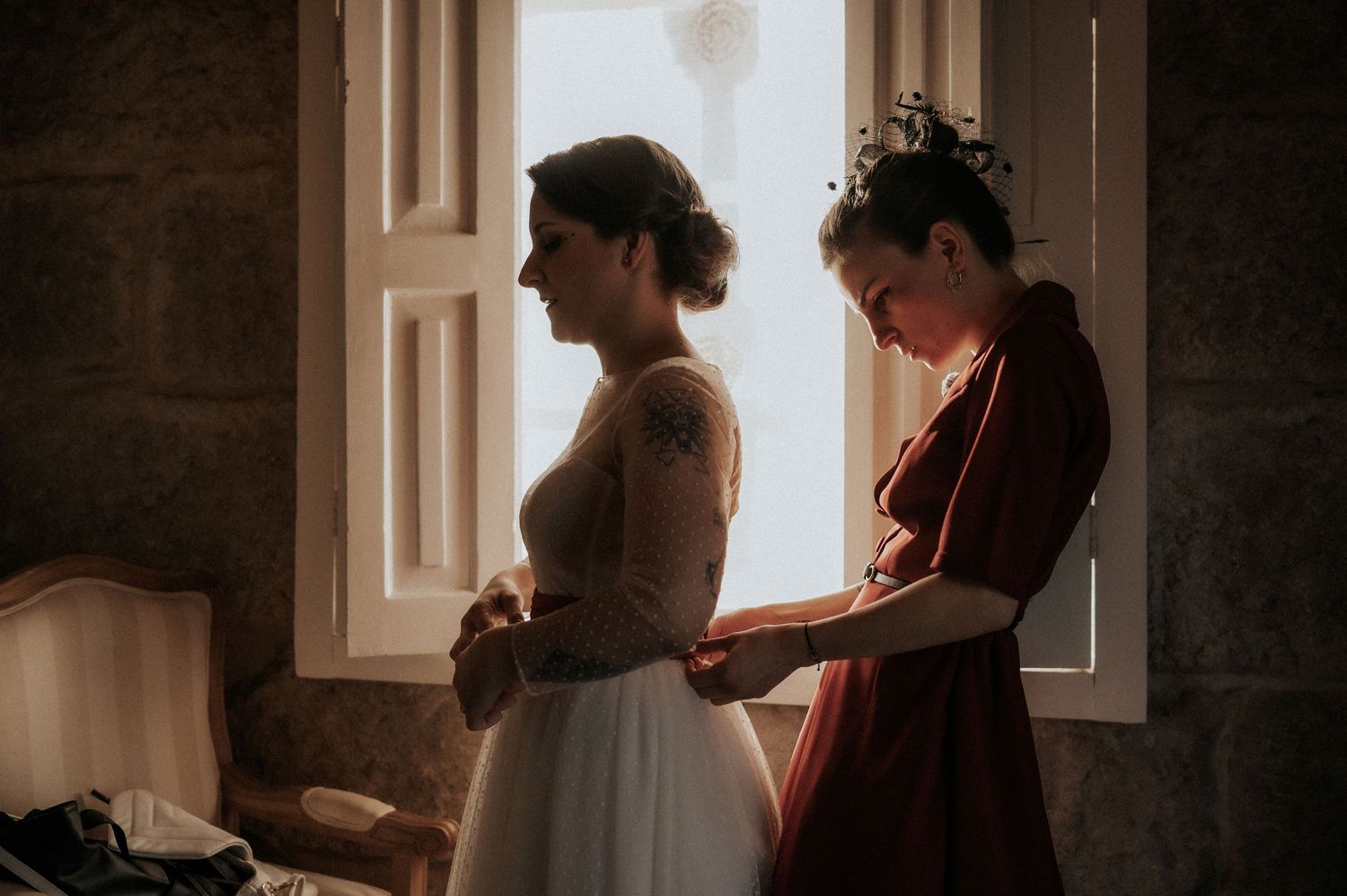A silhouetted figure stands in front of a bright window while reading a book in a moody, atmospheric setting.
